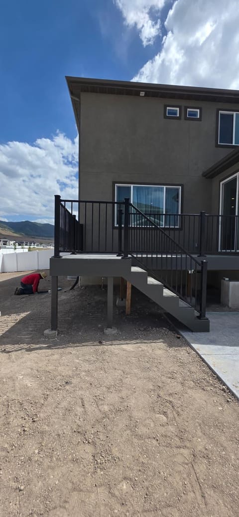 Same composite deck build from a side angle showing stairs, post supports, and Utah mountains beyond — by CasaMás Construction