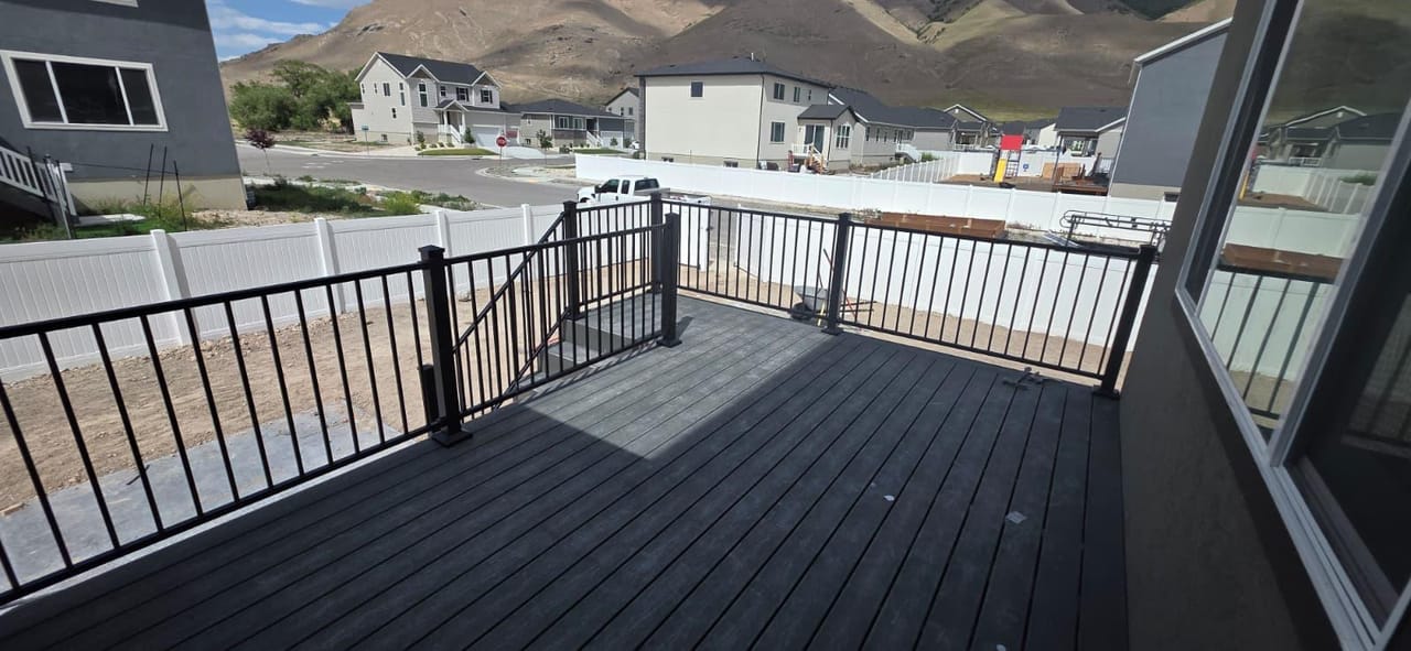 Gray composite deck with black railing overlooking Utah suburb and mountain backdrop, construction-stage view — by CasaMás Construction