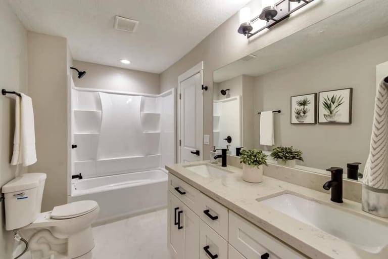 Family bathroom with combined tub and shower, double vanity, white cabinetry, and botanical artwork — Utah family bathroom by CasaMás Construction