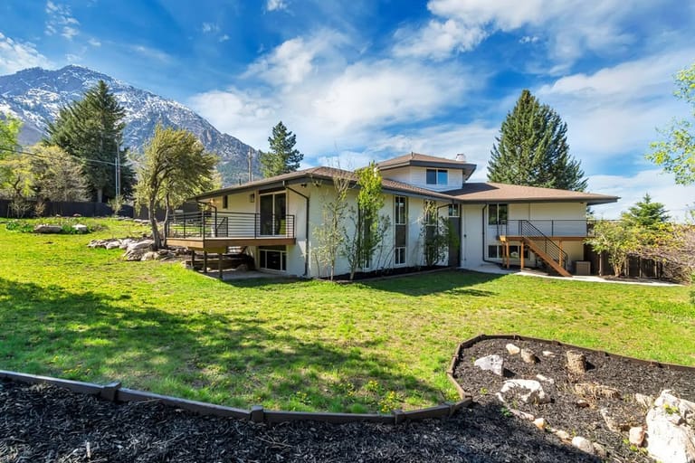 Mid-century home with rear deck addition framed by snow-capped Wasatch peaks — Utah home addition by CasaMás Construction